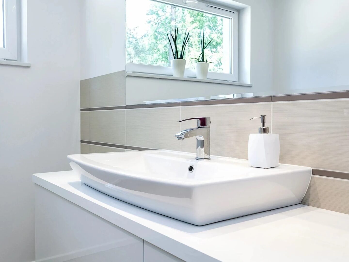 A white sink sitting under a window in the bathroom.