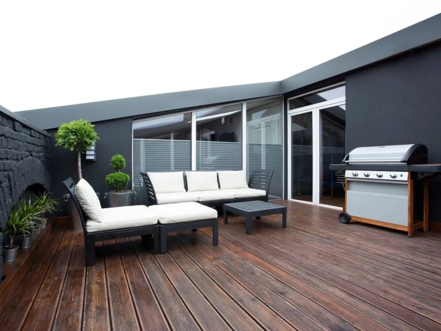 A patio with furniture and a grill on the back deck.