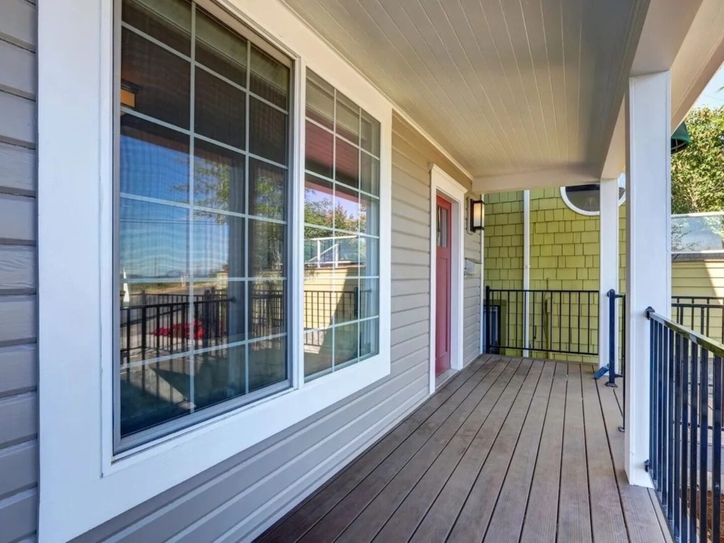 A porch with windows and a balcony in the background.