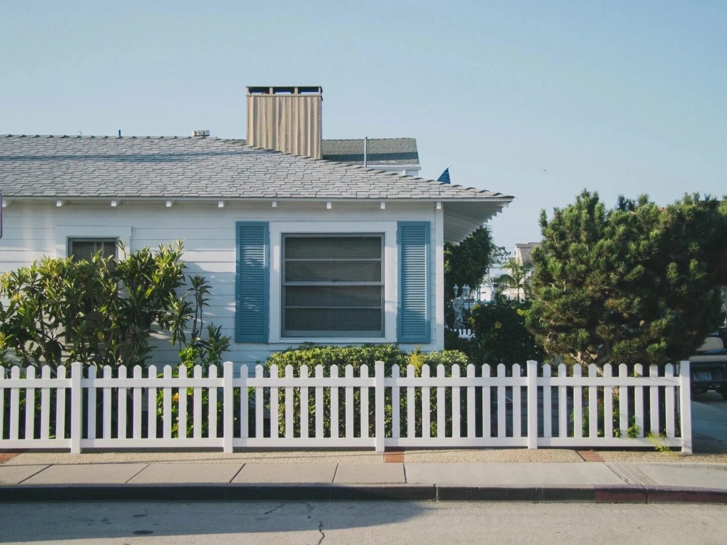 A house with white picket fence and blue shutters.