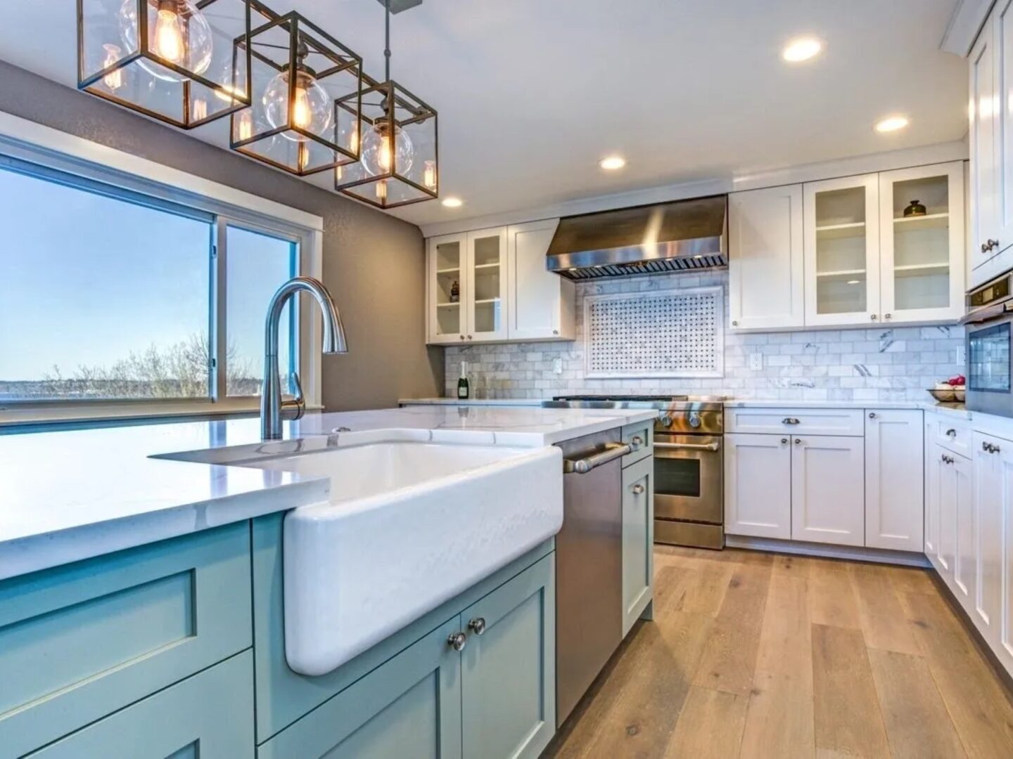 A kitchen with white cabinets and wooden floors.