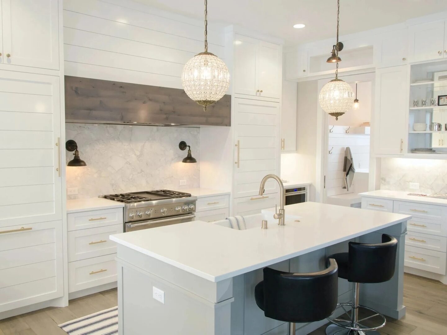 A kitchen with white cabinets and black stools.