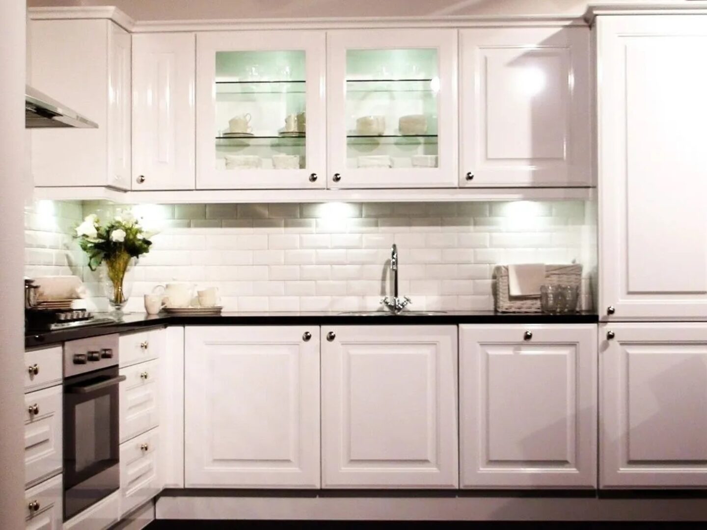 A kitchen with white cabinets and black counter tops.