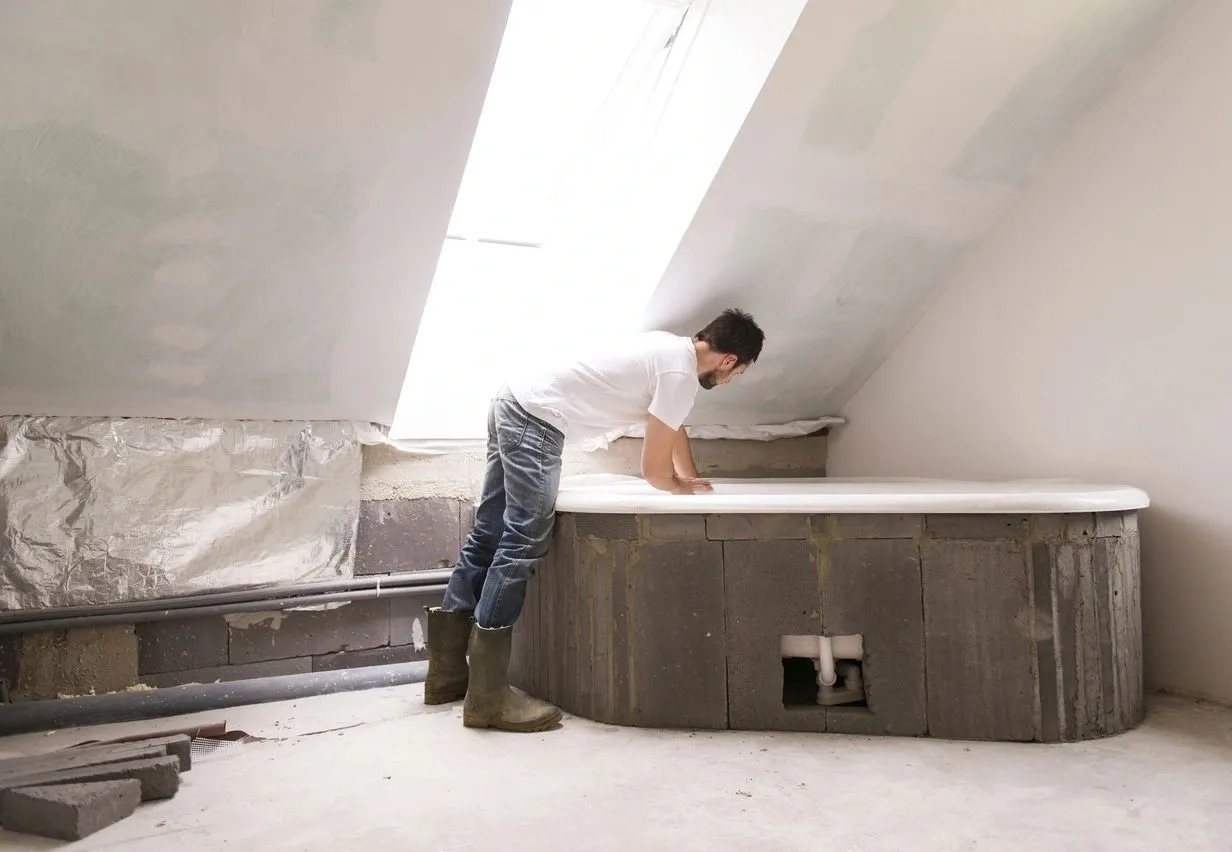 A man in white shirt and boots working on a tub.